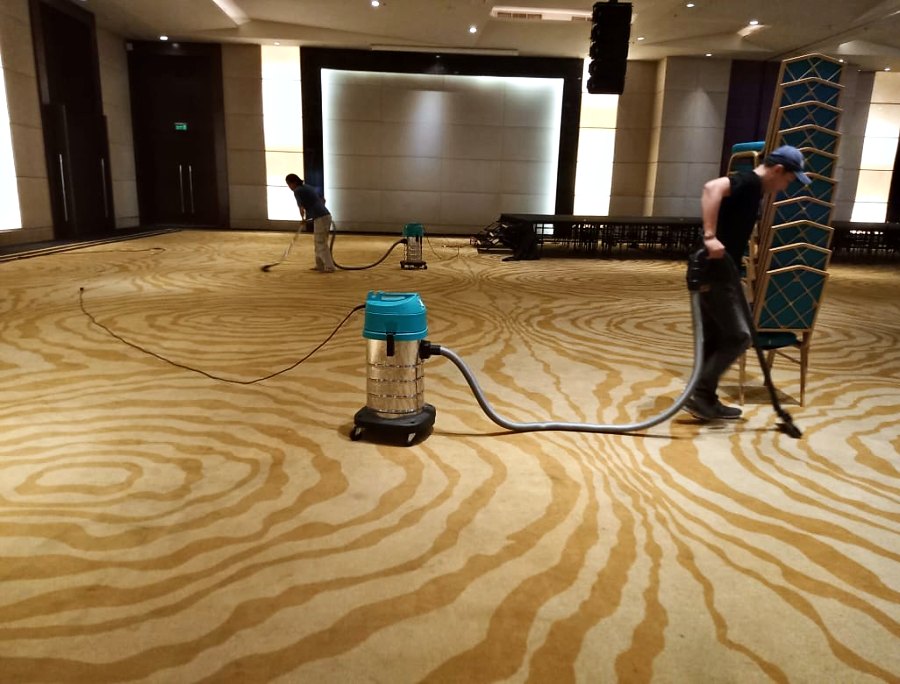 Pekerja memvakum karpet ballroom hotel