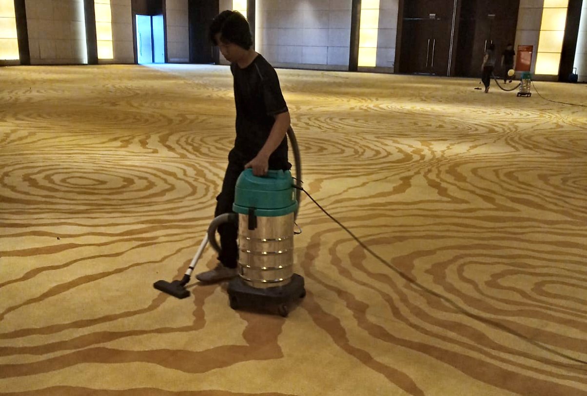 Petugas IndoCareService memvakum karpet ballroom hotel