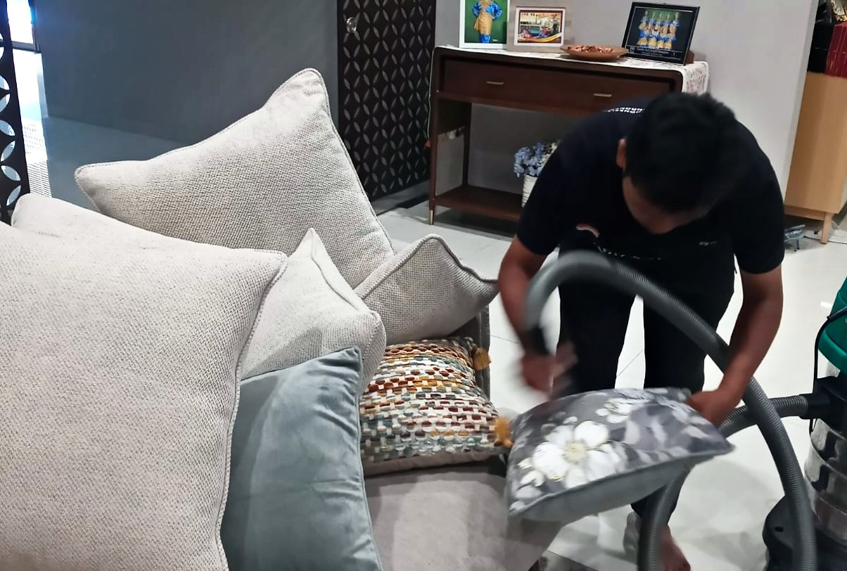 Petugas IndoCareService memvakum bantal sofa