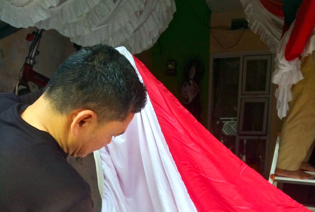 Petugas IndoCareService merapikan bendera merah putih dengan steamer