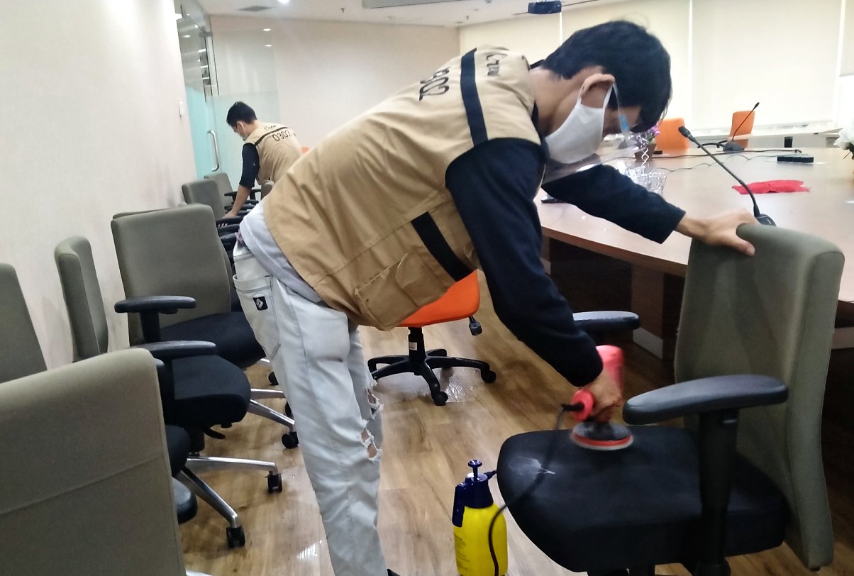 Petugas IndoCareService membersihkan kursi di ruang rapat kantor