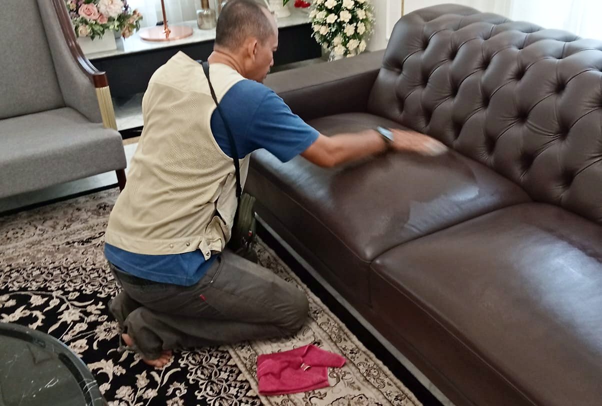 Petugas IndoCareService membersihkan sofa kulit
