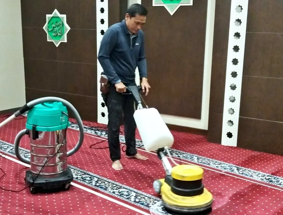 Pekerja membersihkan karpet masjid