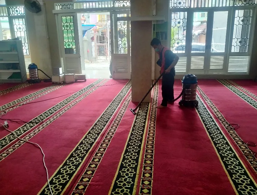 Pekerja memvakum karpet masjid